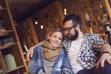 Couple in love sitting in a cafe close to each other, hugging and enjoying their time together. Focus on the girlの写真素材