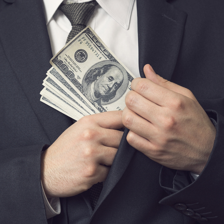 Detail of a man in a suit placing money in his jacket pocket. Selective focusの写真素材