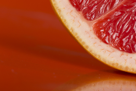Detail of a red grapefruit slice isolated on red background. Selective focusの写真素材