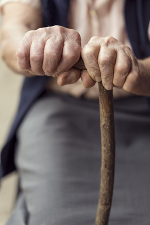 Detail of an elderly woman's hands holding a cane. Selective focusの写真素材