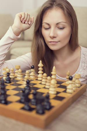 Portrait of a beautiful young pensive brunette planning her next move while playing chessの写真素材
