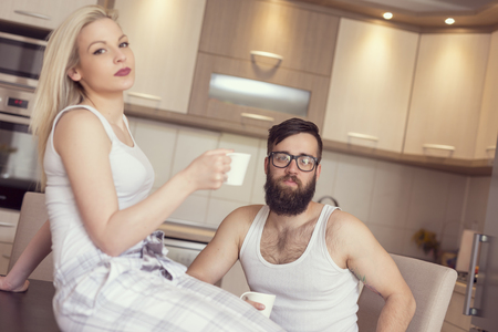 Young couple in love sitting at the table in the kitchen, drinking morning coffee and chattingの写真素材
