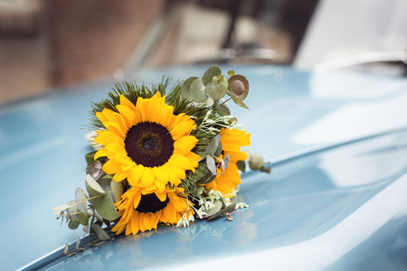 Detail of a sunflower wedding bouquet on a retro old car's hoodの写真素材