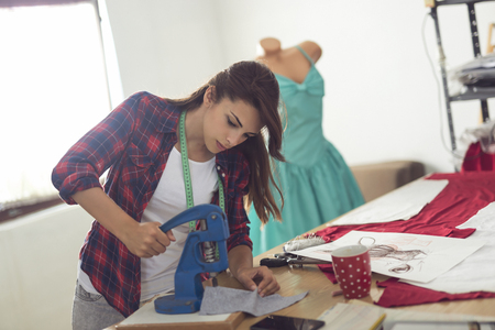 Young dressmaker working in her atelier, putting buttons on the fabricの写真素材