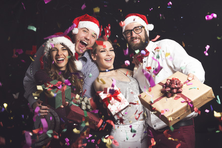 Two couples having fun at New Year's party and holding nicely wrapped present boxesの写真素材