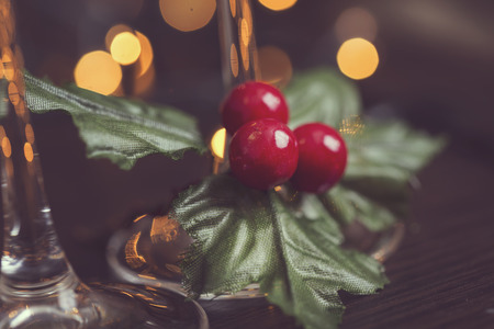 Detail of two champagne glasses placed on the table with mistletoe and Christmas tree and lights in the background. Selective focusの写真素材