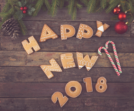 Table top shot of nicely decorated Christmas cookies shaped like letters Happy New 2018 with candy cane, pine cone and fir tree branchesの写真素材