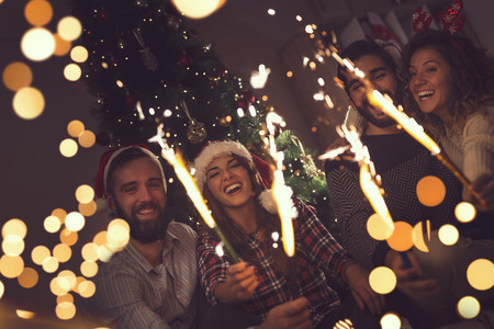 Group of young friends having fun at a New Year's celebration, holding sparklers at a midnight countdown.の写真素材