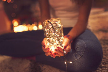 Detail of female's hand holding a jar filled with Christmas lights. Selective focusの写真素材