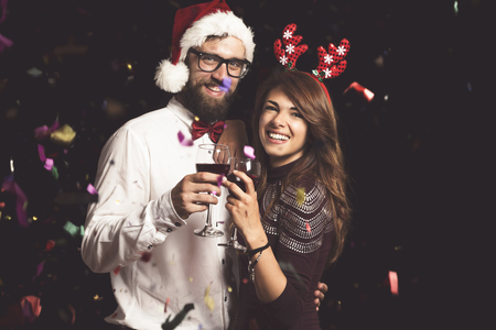 Beautiful young couple in love having fun at a party, holding wine glasses and making a toastの写真素材