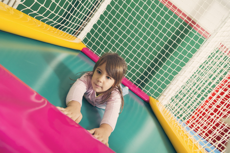 Cheerful child playing on a trampoline in a playroomの写真素材