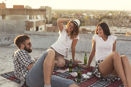 Young people chilling out and partying on a building rooftop. Focus on the girl in the middleの写真素材