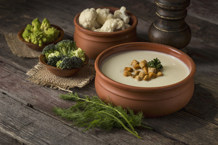 Cauliflower cream soup decorated with some croutons on a rustic wooden table. Selective focus on the croutonsの写真素材
