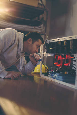 Programmer setting up a mining rig for cryptocurrency miningの写真素材