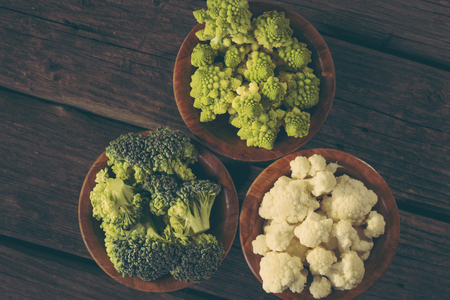 Top view of fresh pieces of romanesco broccoli, broccoli and cauliflower in small rustic wooden bowls. Selective focusの写真素材