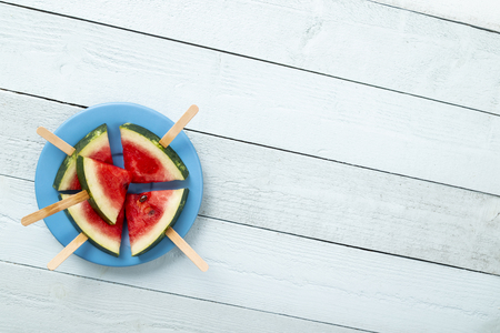 Table top shot of watermelon popsicles on a plate on rustic light blue wooden tableの写真素材
