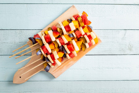 Table top shot of a colorful cold mixed fruit salad served on barbecue sticks as a summertime dessertの写真素材