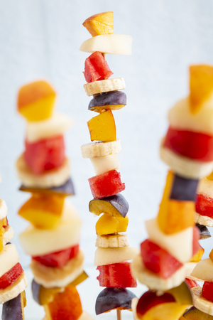 Colorful mixed seasonal fruit salad served on barbecue sticks, stuck in a watermelon half as a summer party dessert. Focus in the central part of the frame on the fruit stickの写真素材