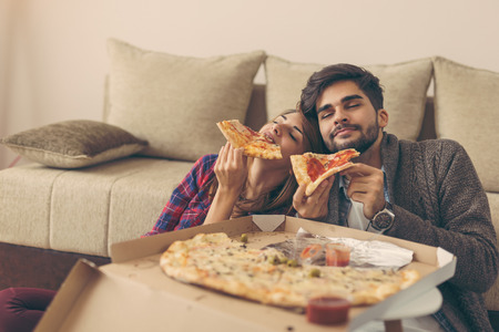 Couple in love eating pizza and having fun. Focus on the guyの写真素材