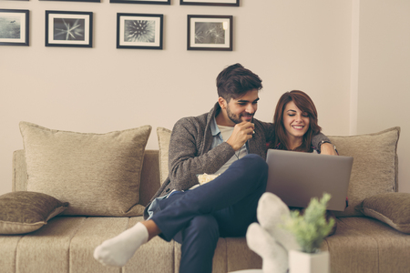 Young couple in love reading news on a laptop computer. Focus on the guyの写真素材
