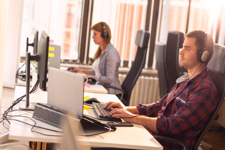 IT support team working in an office; call centre operators wearing headsets and typing on a...