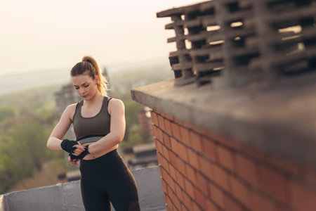 Woman wrapping hands with bandages before workout on a building rooftop terrace