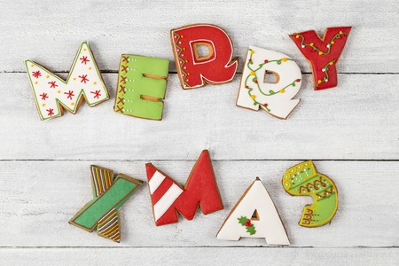 Top view of colorful, nicely decorated gingerbread Christmas cookies shaped as letters Merry Xmas on white wooden backgroundの写真素材