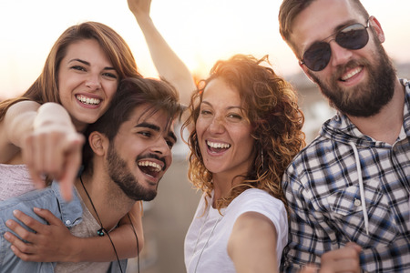 Group of young friends having fun on a summertime rooftop party. Focus on the girlsの写真素材