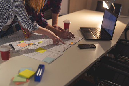 Two business colleagues working overtime in an office, analysing contracts. Focus on the woman's fingerの写真素材