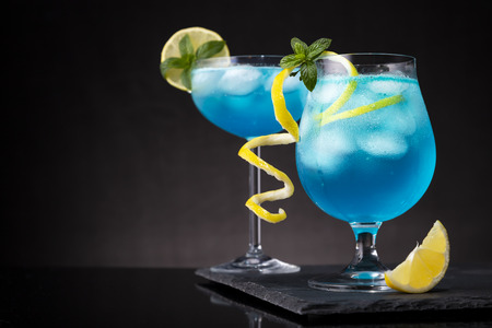 Blue lagoon cocktails with blue curacao liqueur, vodka, lemon juice and soda, decorated with lemon slice and mint leaves. Selective focus on the mint leavesの写真素材