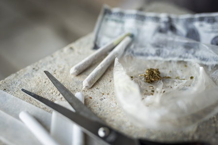 High angle view of rolled joints and marijuana buds in a bag. Selective focus on the top of the closer jointの写真素材