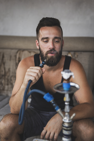 Man inhaling fruity flavored, molasses based tobacco using a water pipe, hookah or narghileの写真素材