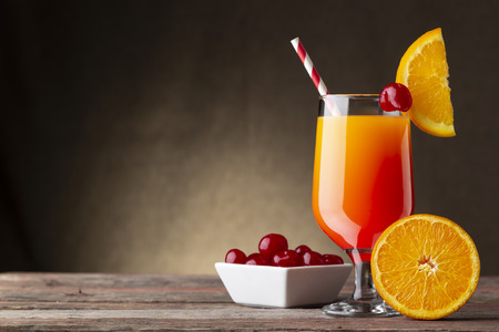 Cold tequila sunrise cocktail with tequila, pomegranate juice and orange juice decorated with slices of orange and maraschino cherriesの写真素材