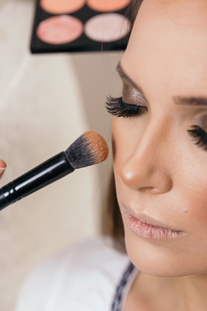 Make up artist working in a make up studio, applying blush to female client's cheeksの写真素材