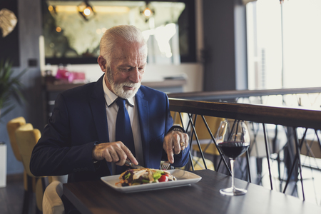 Senior businessman taking a break, having lunch in a restaurantの写真素材