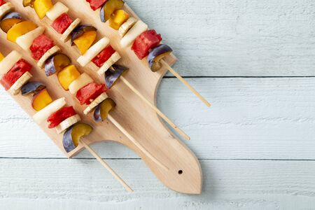 Table top shot of a colorful, healthy fruit salad portions served on barbecue sticks as a summer dessertの写真素材