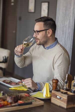 Man on a date in a restaurant eating lunch, drinking wine and having funの写真素材