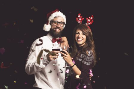 Beautiful young couple in love having fun at a New Year's Eve party, holding wine glasses and making a toast at midnightの写真素材