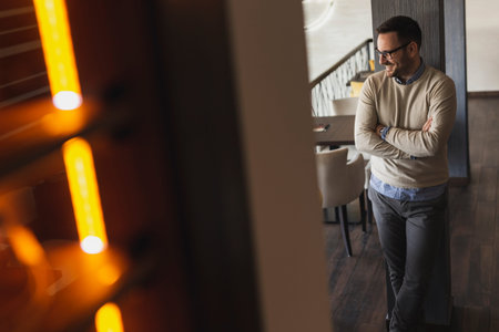 Handsome man standing in a restaurant, looking at the distance, smiling