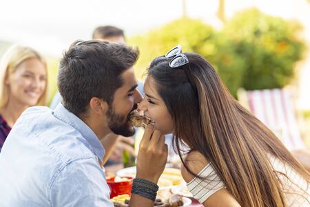 Couple having fun at a backyard barbecue party, sharing a skewerの写真素材