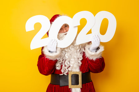 Santa Claus holding cardboard numbers 2020 as an announcement of the upcoming New Year and seasonal...