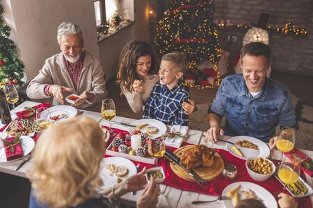 Beautiful happy family gathered around the table, having Christmas dinner all together at homeの写真素材