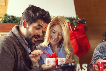 Couple having fun while celebrating Christmas at home, exchanging Christmas presentsの写真素材