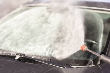 Detail of washing a car windshield with high pressure hot water and detergent in a car washの写真素材
