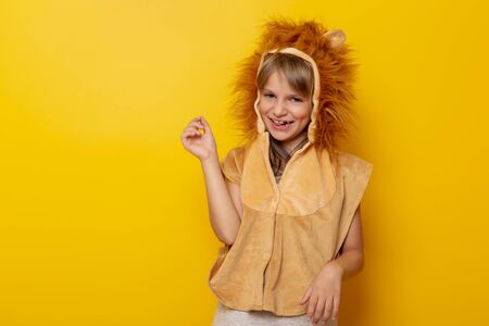 Beautiful little girl wearing lion carnival costume isolated on yellow colored backgroundの写真素材