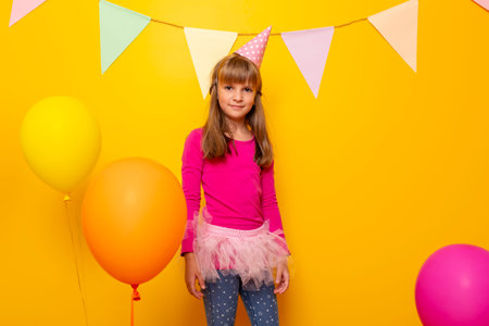 Beautiful little girl having fun celebrating her birthday, playing with bunch of colorful balloons,...