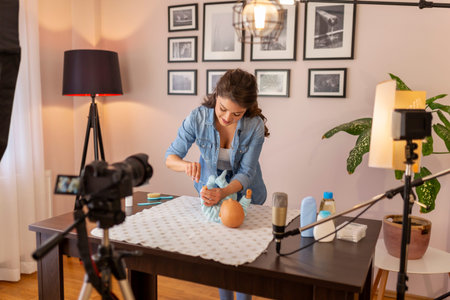 Influencer filming video about newborn baby nail clipping with scissors as part of online prenatal...