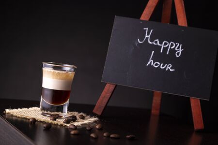 B-52 layered cocktail shot on a burlap coaster decorated with fresh roasted coffee beans placed on a bar counter with copy spaceの写真素材