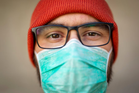 Portrait of man wearing medical face protection mask; air pollution or allergies protection,...