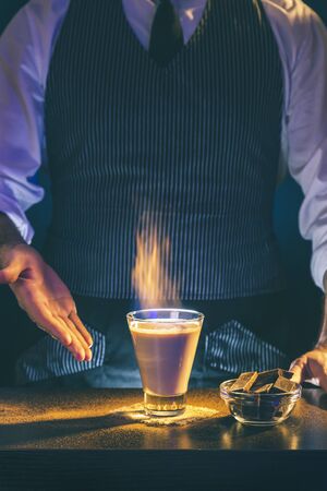 Bartender serving flaming Baileys comet cocktail; Irish cream cocktail on fire served on a bar counterの写真素材
